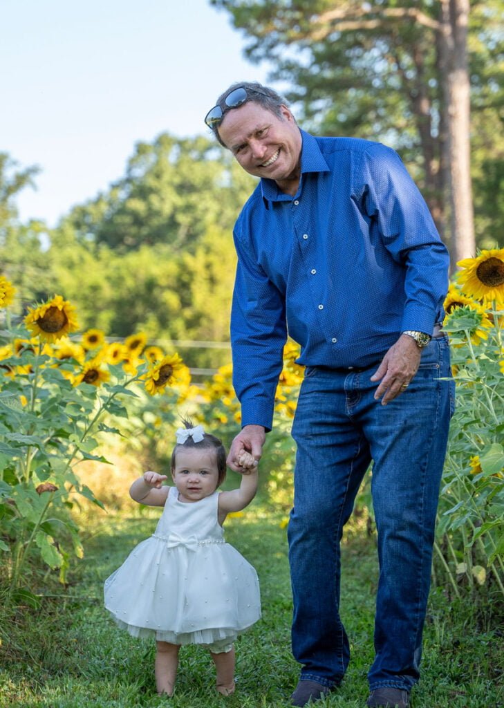 Spring and Summer Flower Themed Photoshoot Mini Session Ideas with grandfather and granddaughter in a field of sunflowers