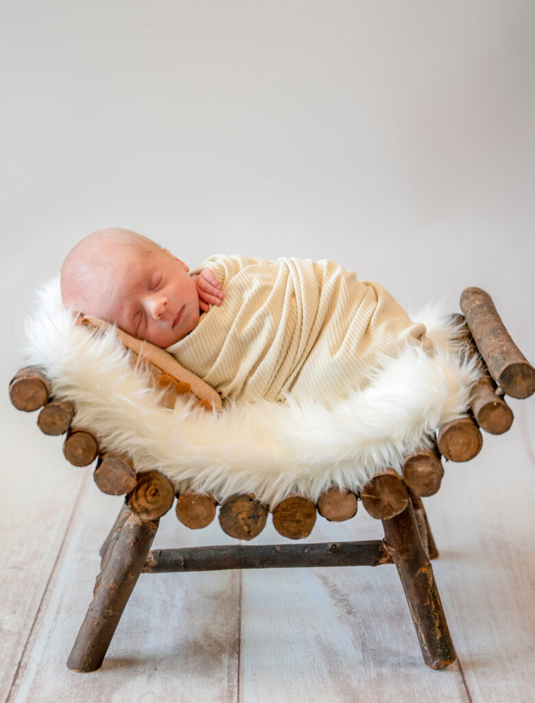 Newborn photography with infant swaddled sleeping peacefully at home