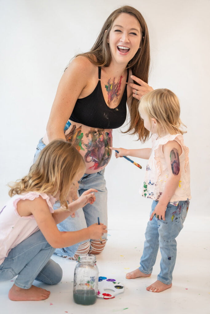 Toddlers painting mommy's belly bump for maternity shoot and pregnancy announcement